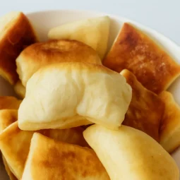 Jogurt uštipci prikazani u zdjeli – mekani, zlatno pečeni domaći uštipci s hrskavom površinom.