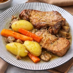 Pečeni svinjski kotleti s krumpirom, mrkvom i šampinjonima servirani na tanjuru
