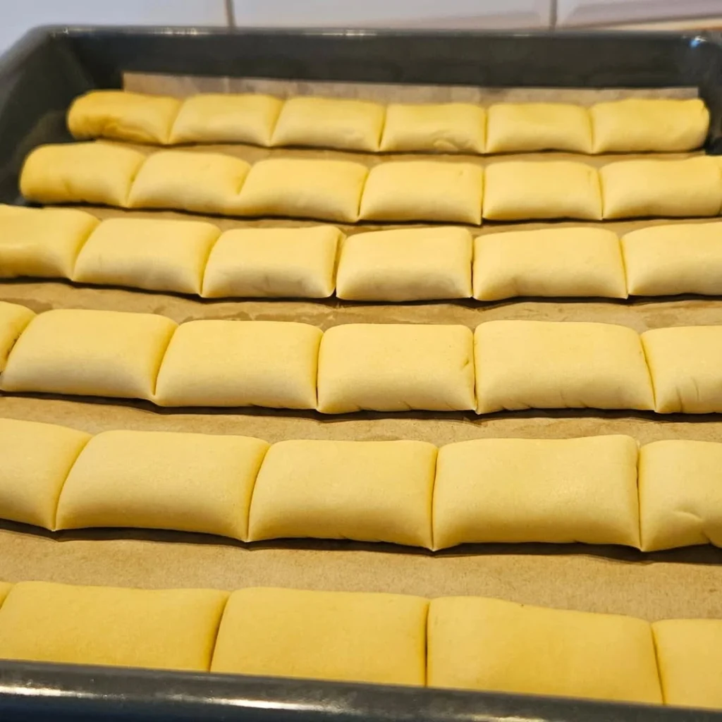 Narezane štrudlice s pekmezom složene u pleh na papir za pečenje – priprema prije pečenja domaćih kolačića