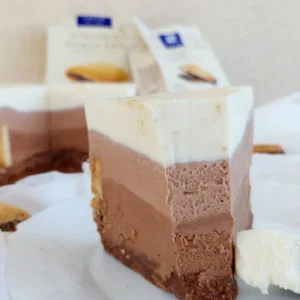 Detalj zalogaja cheesecakea na žlici, prikazuje kremastu teksturu bijelog i čokoladnog sloja.