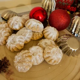 Domaće šape s orasima uvaljane u šećer u prahu, poslužene uz modlice i blagdanske ukrase.