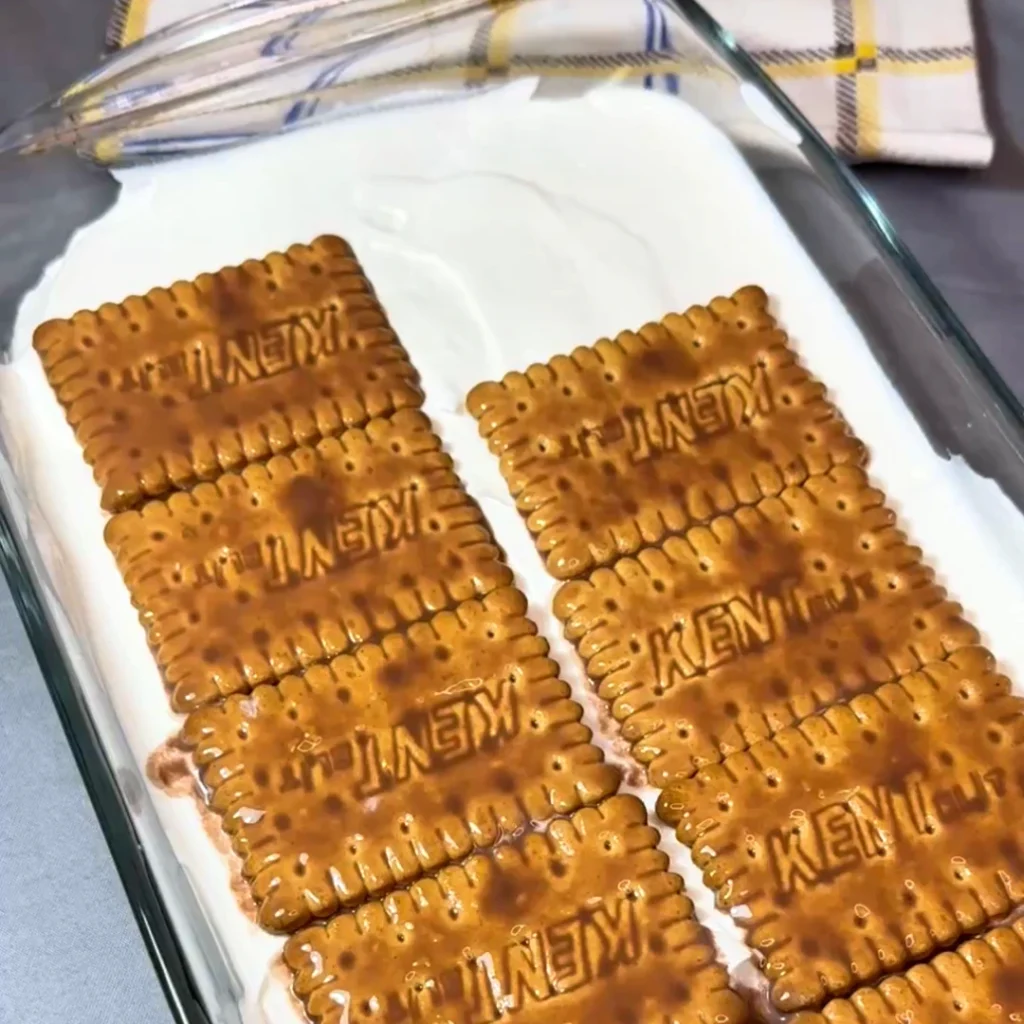 Raspoređivanje drugog reda keksa preko sloja kreme u staklenom plehu