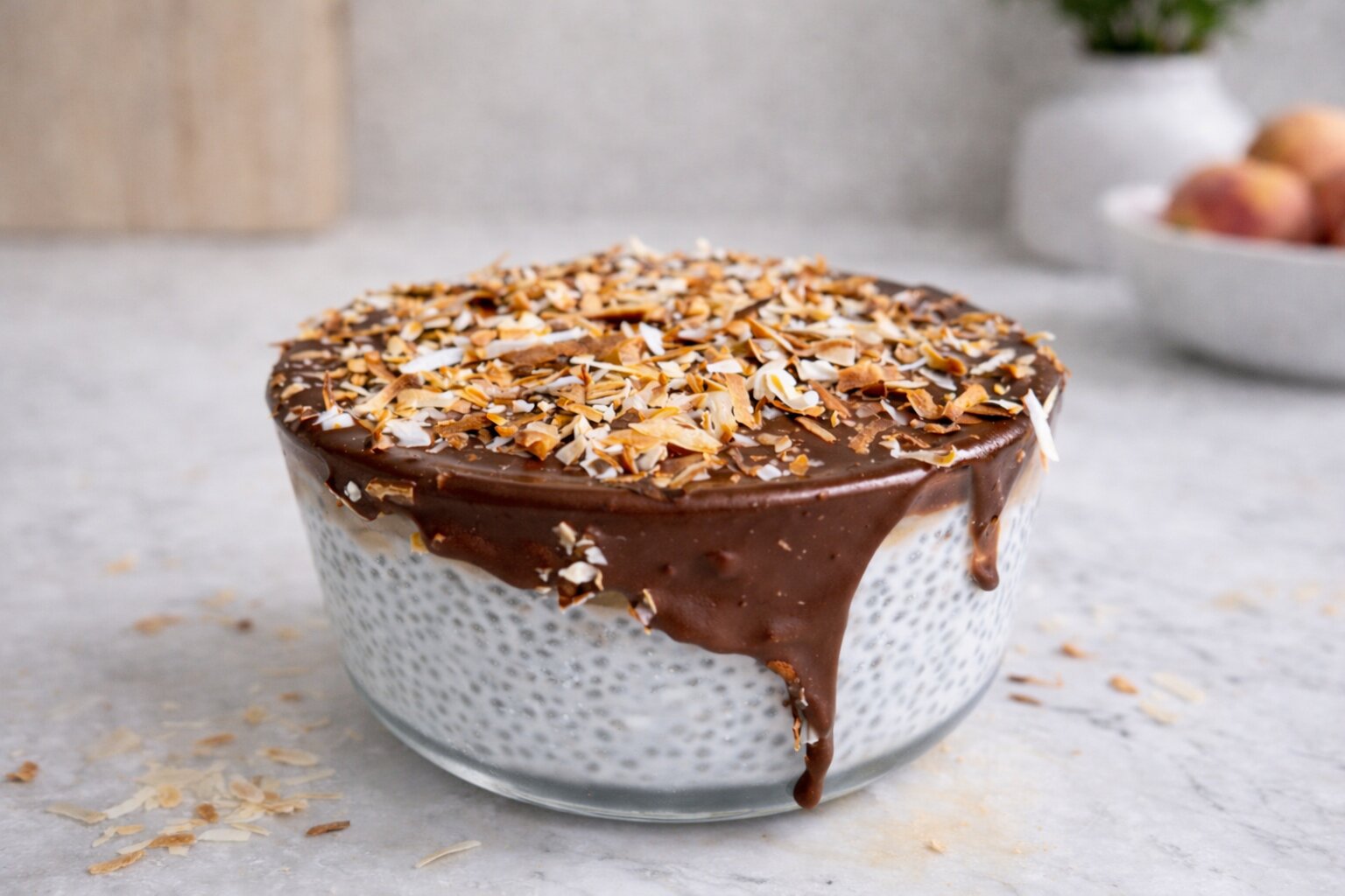 Chia puding u staklenoj posudi s čokoladnim preljevom koji se slijeva niz rub