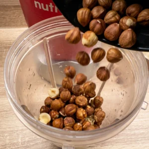 Sipanje pečenih lješnjaka iz crne posude u posudu Nutribullet blendera