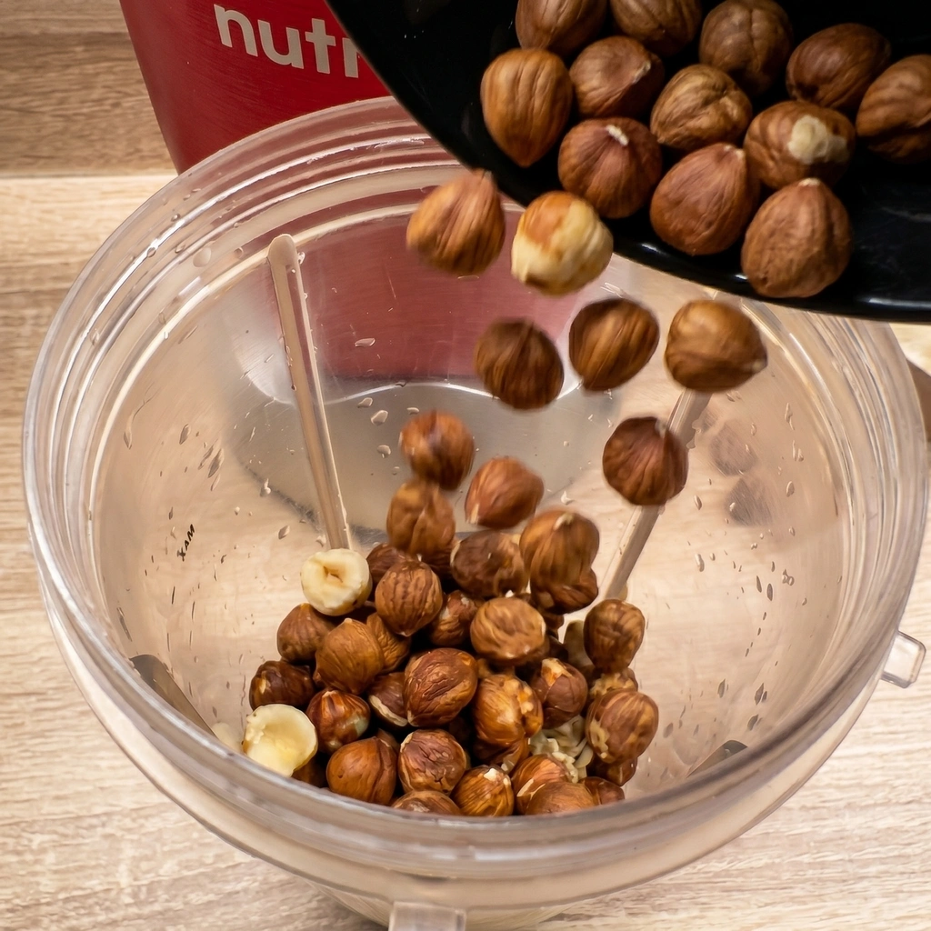 Sipanje pečenih lješnjaka iz crne posude u posudu Nutribullet blendera