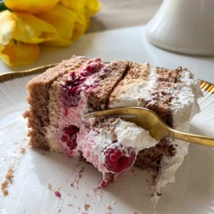Zlatna vilica uzima zalogaj čoko moko torte s malinama i kremom