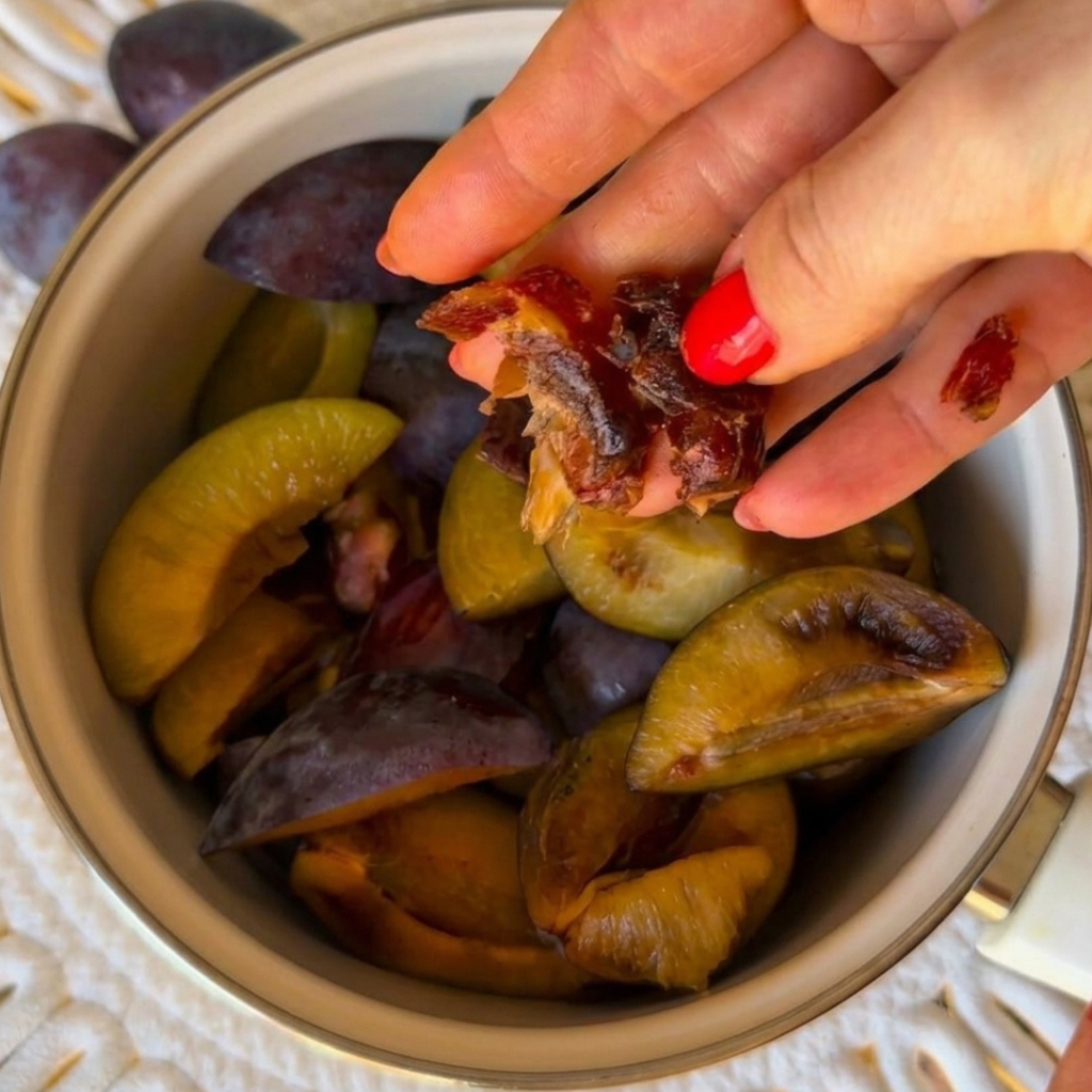 Ruka dodaje namočenu datulju u narezane šljive bez koštica