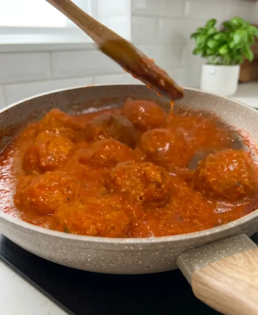 Miješanje vege ćufti od leće drvenom kuhačom u tavi s umakom od rajčice